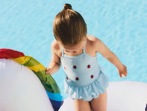 Pige klædt i lyseblå stribet badedragt med broderi af mariehøns og flæseskørt fra Name It 13239671 bonnie blue